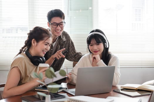 A cheerful and intelligent young Asian man is standing and sharing his thoughts in a meeting with his team. University students, friendship, startups, teamwork.