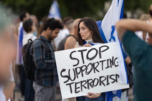Lisbon, Portugal – October 10, 2023: A woman at a rally in support of Israel, in her hands is a poster "Stop supporting terrorism". Mid. shot