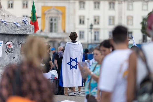 Lisbon, Portugal October 10, 2023. A woman at a rally in support of Israel, with the flag of Israel on her shoulders. Mid. shot