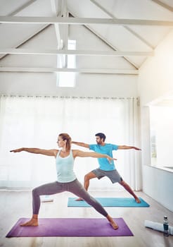 Couple, yoga and stretching in studio workout, exercise and holistic training with balance, pilates or fitness. People or personal trainer in warrior pose for wellness, health and learning together.