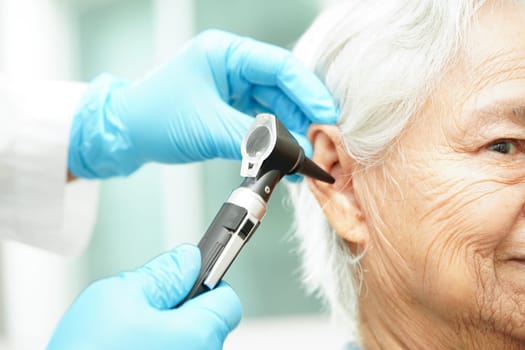 Otolaryngologist or ENT physician doctor examining senior patient ear with otoscope, hearing loss problem.