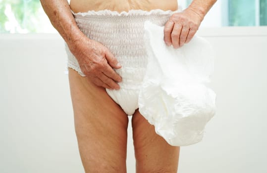 Asian senior woman patient wearing adult incontinence diaper pad in hospital.