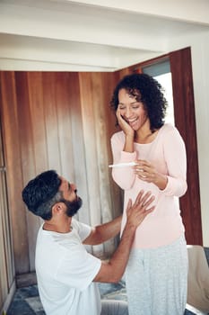 Couple, surprise and stomach with pregnancy test, positive and bed with smile, results and excited. Man, woman and baby with stick, love and maternity for future family, happy and pregnancy together.