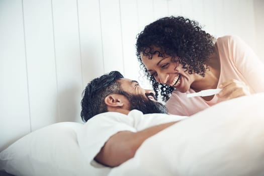 Couple, happy and laughter with pregnancy test, positive and bed with smile, results and excited. Man, woman and baby with stick, love and maternity for future family, surprise and pregnant together.