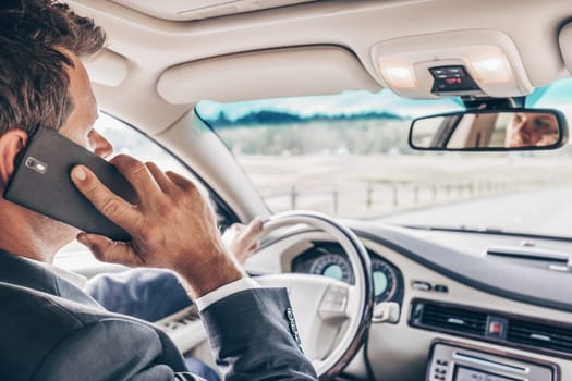 Businessman talking on cell phone while driving and overtaking, not paying attention to the road and traffic.