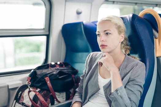 Blonde caucasian business woman traveling by train. Business travel concept.