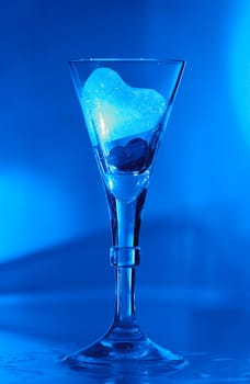 Ice heart and heart in a glass illuminated with blue light.