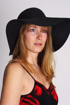 Photo shows a woman in a hat,looking into the distance.