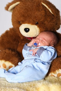 Photo shows a sleeping baby with a cuddly toy (bear)