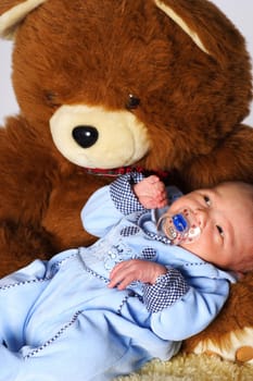 Photo shows a newborn baby looking at the stuffed bear with open eyes