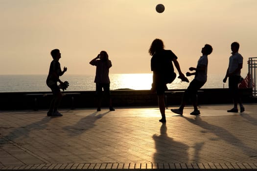 Children playing football in the last evening sun on the beach of Levanto.