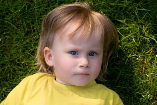 A little girl lying on a green meadow
