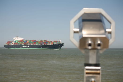 A large container ship passes the viewpoint at the Alte Liebe in Cuxhaven