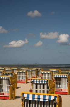 Beach chairs on the sandy beach of Cuxhaven-Duhnen,on the horizon the Hallig Neuwerk