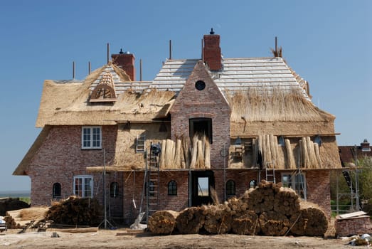 A North German house with a thatched roof is built