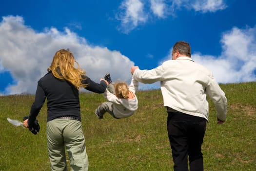 A small family on a walk,father and mother pick up the child