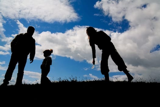 Silhouettes of a small family on a hill under backlight