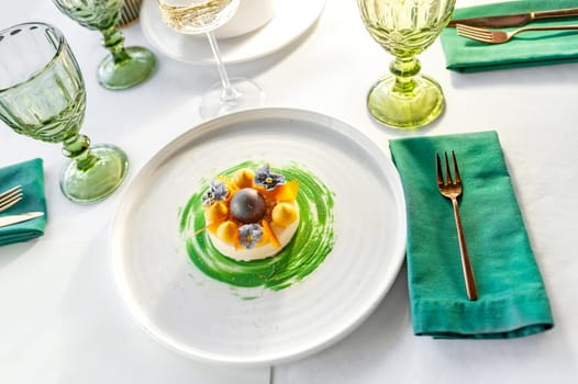 Gourmet dessert with mango meringue on a white plate on a table in a restaurant