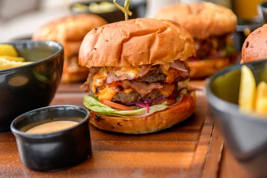 Street food, fast food. Homemade juicy burgers with beef, cheese and caramelized onions on the wooden table.