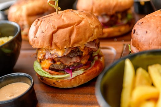 Street food, fast food. Homemade juicy burgers with beef, cheese and caramelized onions on the wooden table.