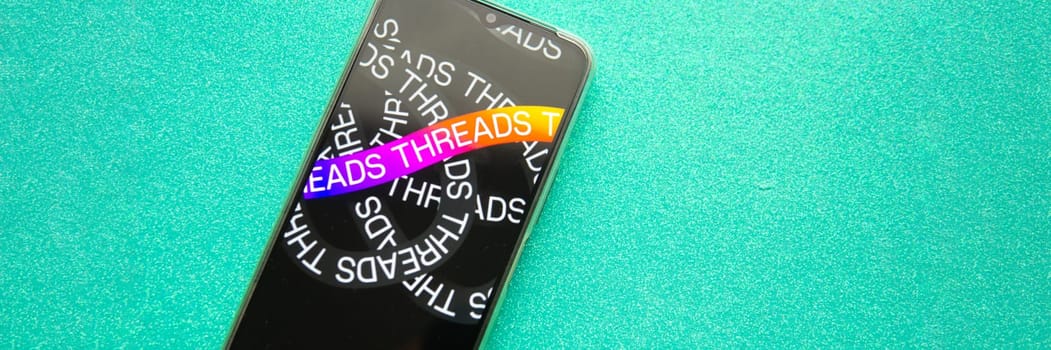 Tver, Russia - July 15, 2023, threads logo on the smartphone screen, on a green background. The threads icon. The logo of the current application. Threads social network