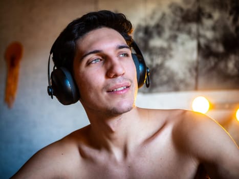 Attractive Young Man Using Headphones Lying Alone On His Bed, Listening to Music and Having a Good Time