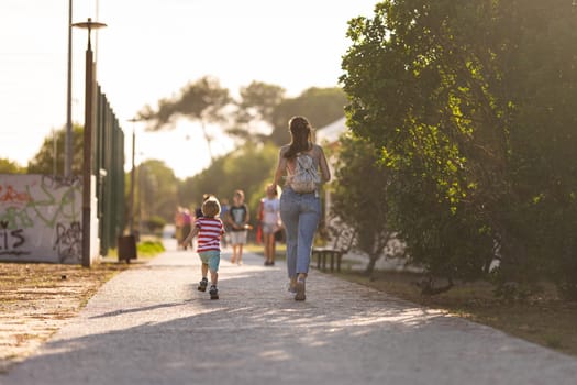 Cute blond boy climbing walking in the park with his mother in a holiday. Mid shot