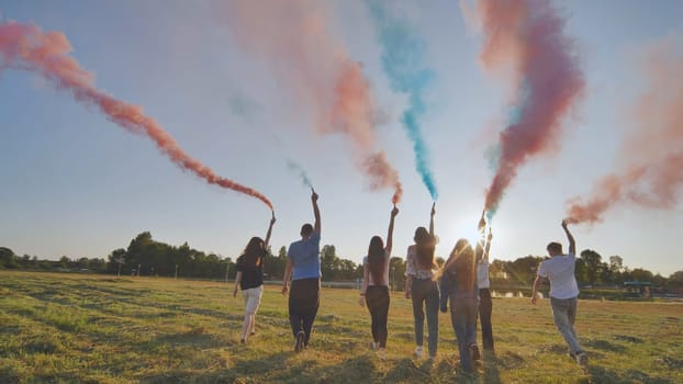 A group of friends spraying multi-colored smoke at sunset