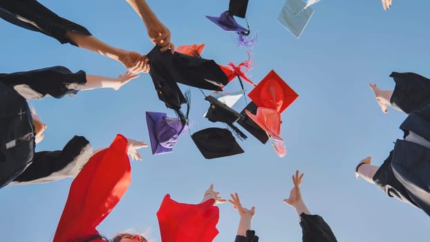 Graduates tossing multicolored hats against a blue sky