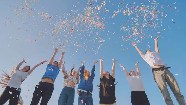 Friends toss colorful paper confetti from their hands