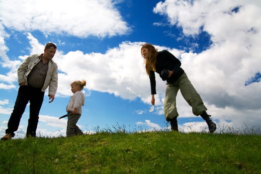 A family on a hill in front of a blue sky with a few clouds