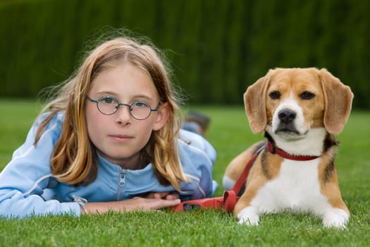 A girl lies next to her dog on the lawn