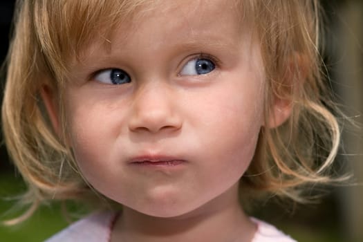 Close-up of a little girl grimacing and rolling her eyes.