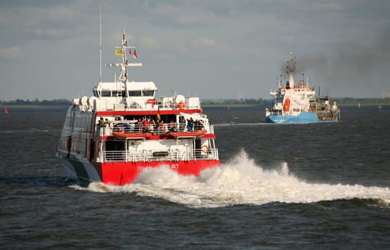 This motor catamaran sails almost daily to Heligoland. The blue ship in the background is a dredging ship.