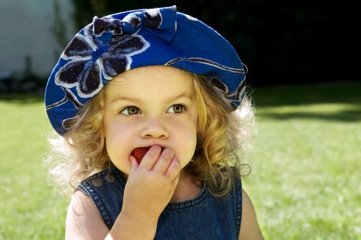 Child bites into a strawberry with relish