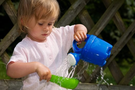 A little girl playing with a watering can