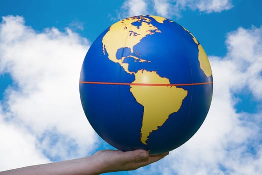 A globe in one hand in front of a blue sky,the world in our hands