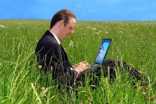Businessman with notebook on the meadow