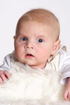 A surprised-looking boy lies on a white coat