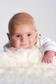 Little baby lies laughing on a white fur