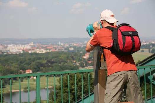 Backpacker at a coin-operated telescope over Dresden