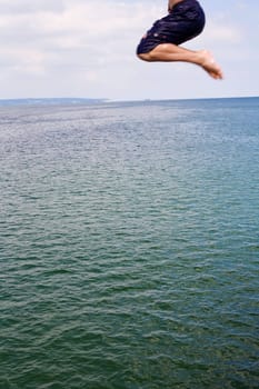 A young man jumps into the water,only the legs can be seen in motion blur