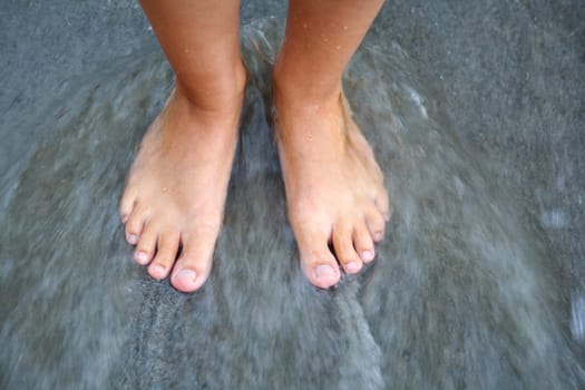 Women's feet in the sea washed by water
