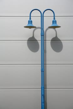 Blue street lamp in front of a house wall