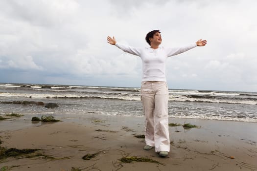 A teenager stands with outstretched arms on the beach