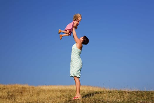 A young girl and a toddler,the toddler is lifted up