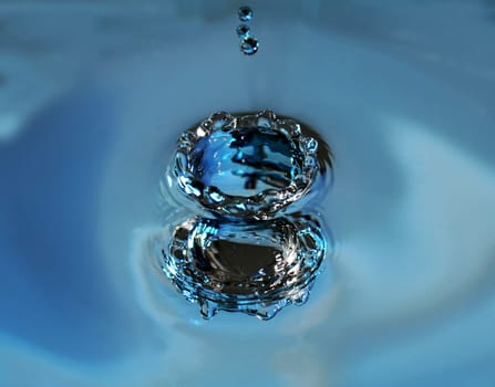 Impact of a drop on the surface of the water from above and seen from below at the same time by reflection (negative form)