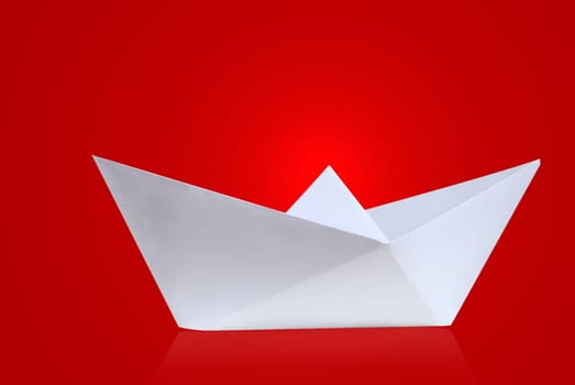 Paper ship against red background