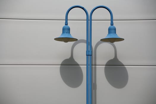Blue street lamp in front of a house wall