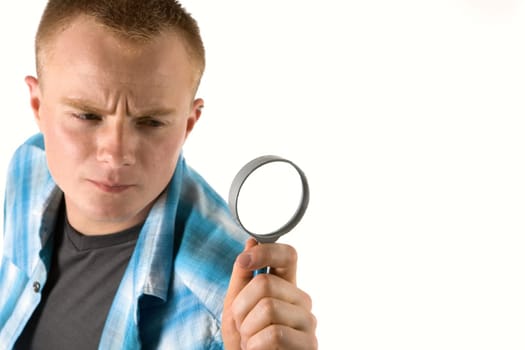 A young man looks through a magnifying glass